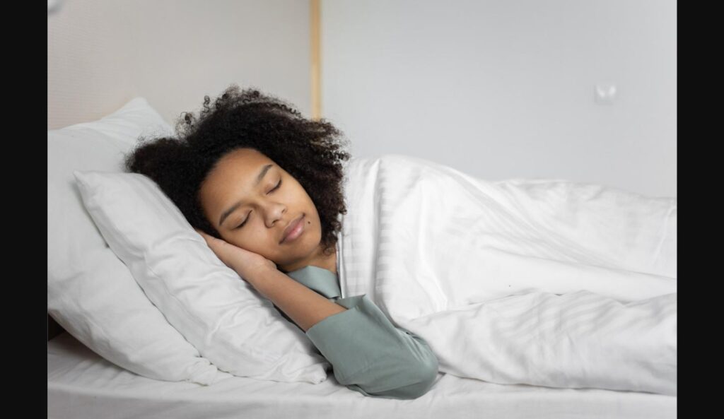 Woman peacefully sleeping in bed, illustrating the mouth taping sleep trend