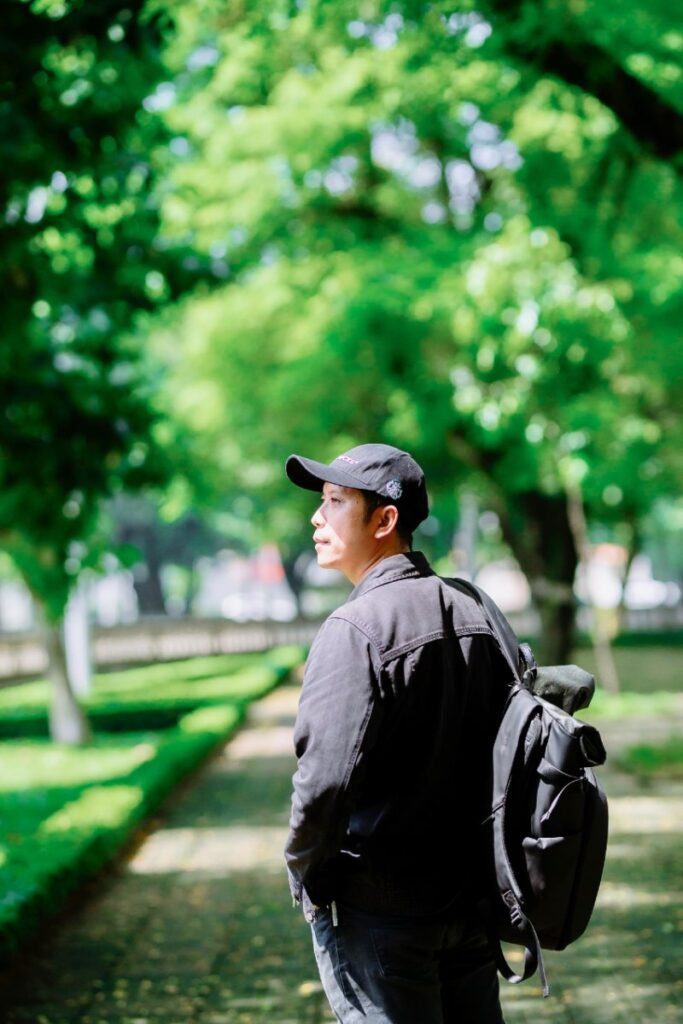Man rucking with a weighted backpack while walking through a green park