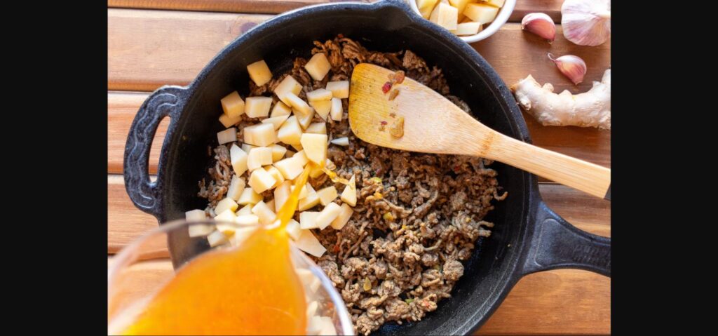 Budget ground beef and rice skillet cooking in a cast iron pan