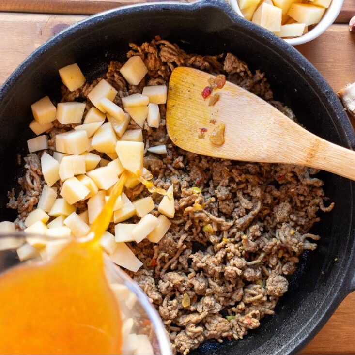 Budget ground beef and rice skillet cooking in a cast iron pan