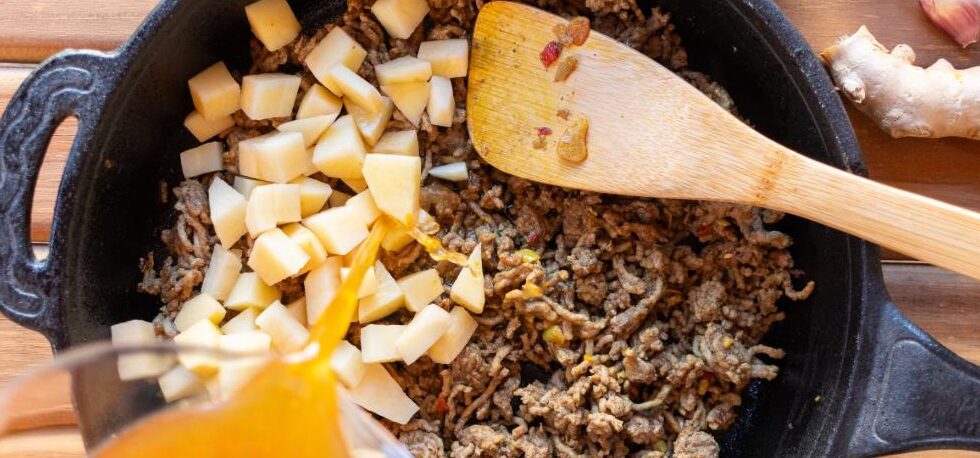 Budget ground beef and rice skillet cooking in a cast iron pan