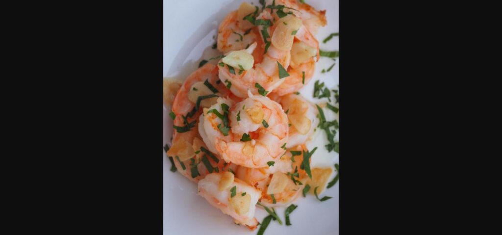 Garlic butter shrimp garnished with parsley on a white plate