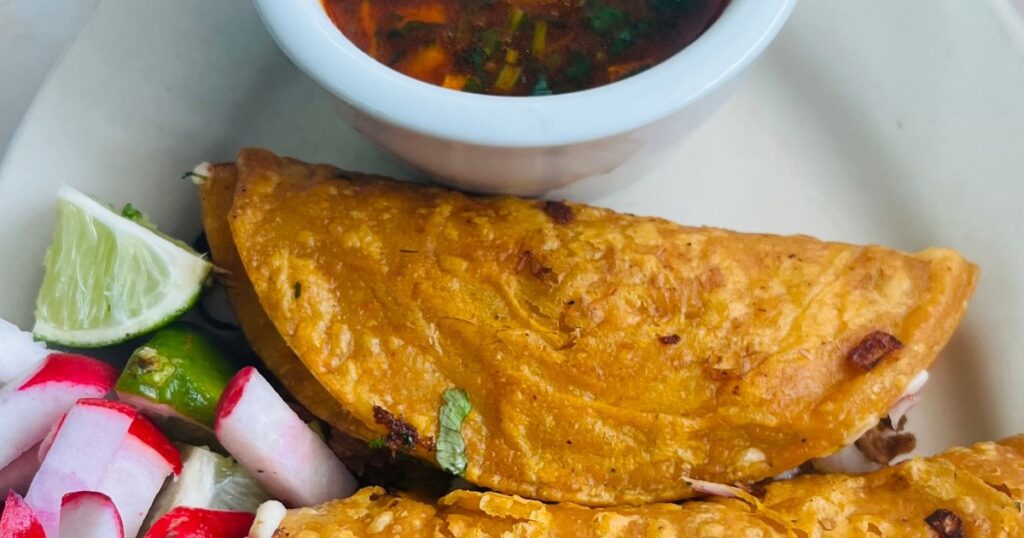 Quick birria tacos with melted cheese and consommé dipping sauce, close-up food photography