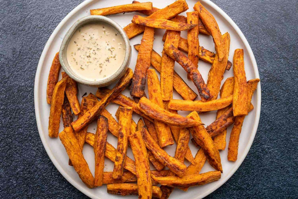 Crispy air fryer sweet potato fries on a plate with creamy dipping sauce