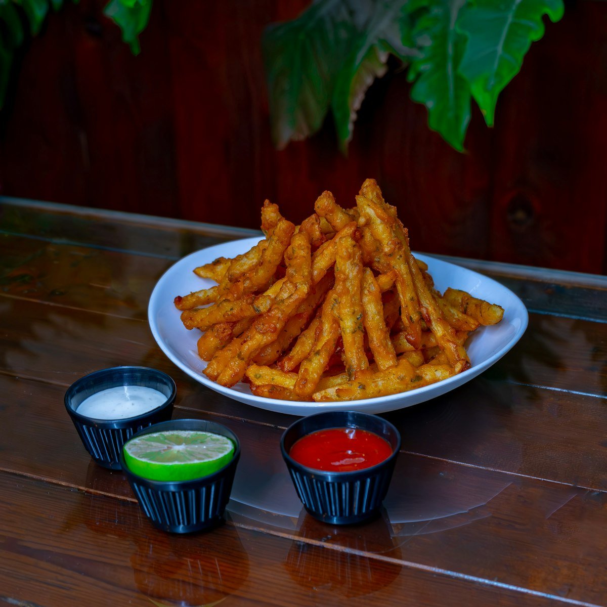 Plate of crispy sweet potato fries served with three dipping sauces