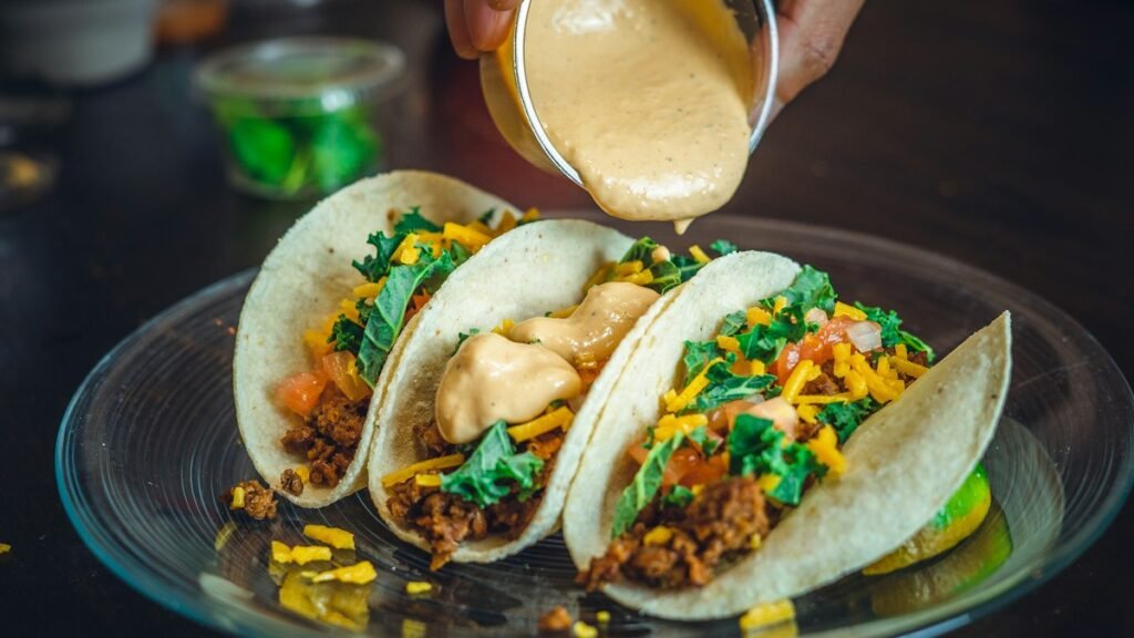 Birria-style beef tacos with consomme being poured
