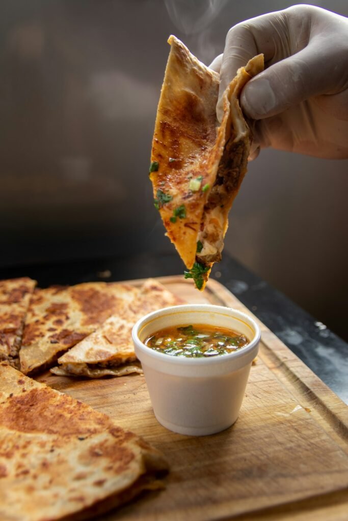 Birria taco dipped into rich beef consomme