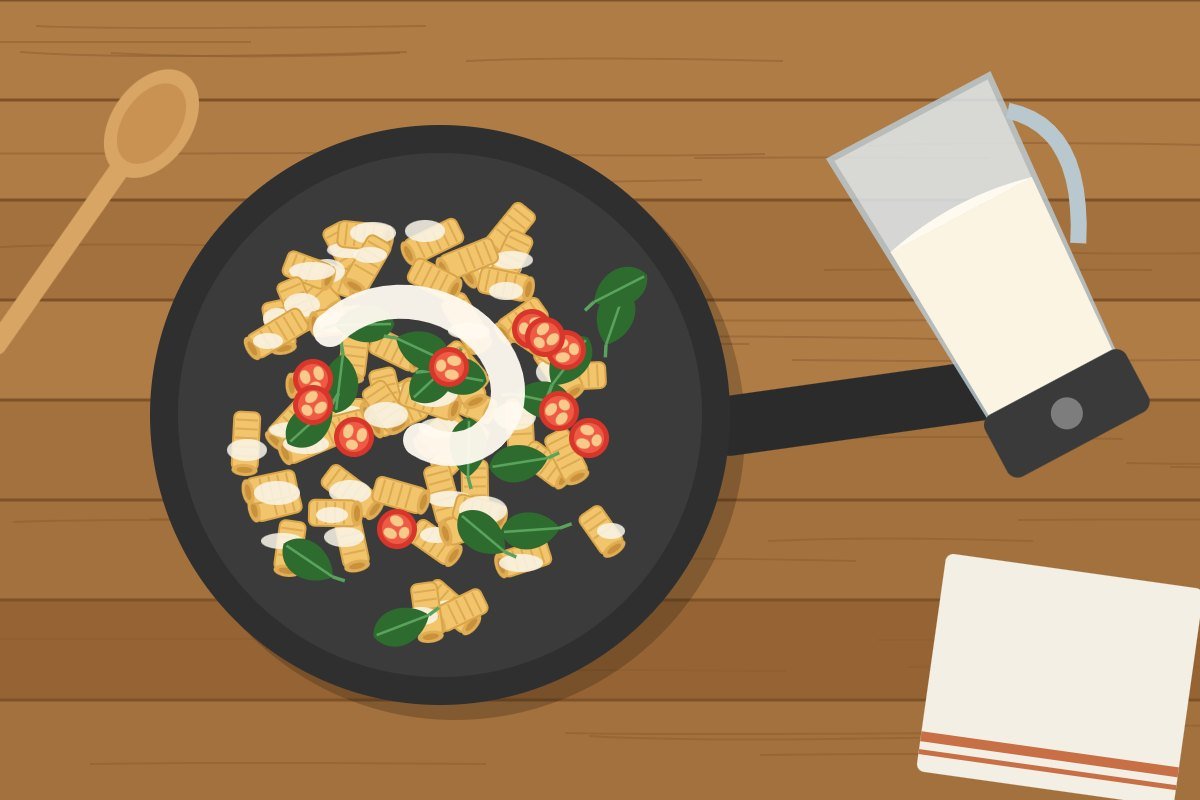 Blended cottage cheese sauce poured over pasta with spinach and cherry tomatoes in a skillet