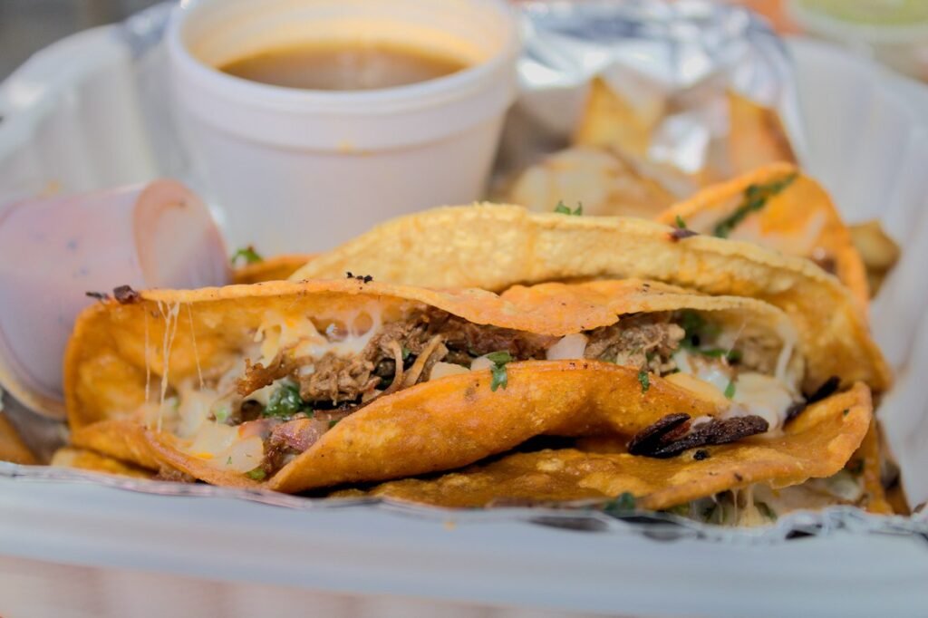 Crispy birria tacos with a cup of consomme