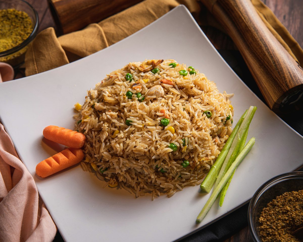 Egg fried rice with peas and carrots served on a white plate