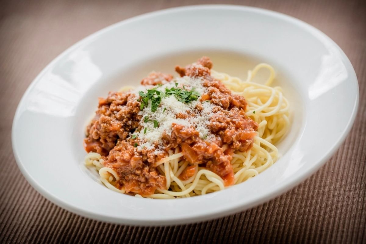 Plated ground beef spaghetti with grated Parmesan and chopped parsley