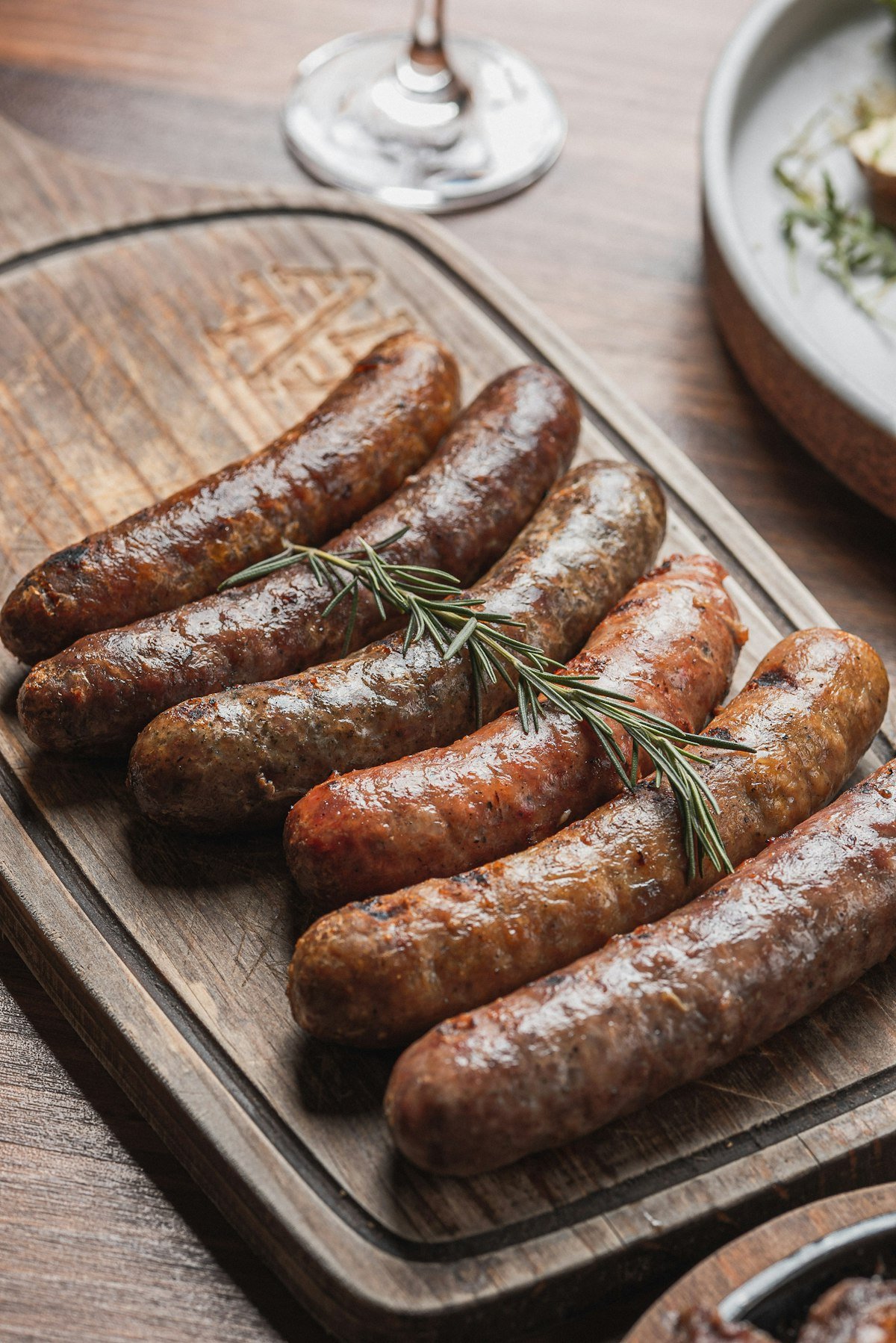 Roasted Italian sausages with rosemary served on a wooden board